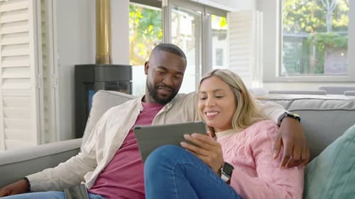 Couple afro-américain faisant défiler une tablette sur un canapé, une invite de paiement apparaissant, un homme tenant une carte achetant