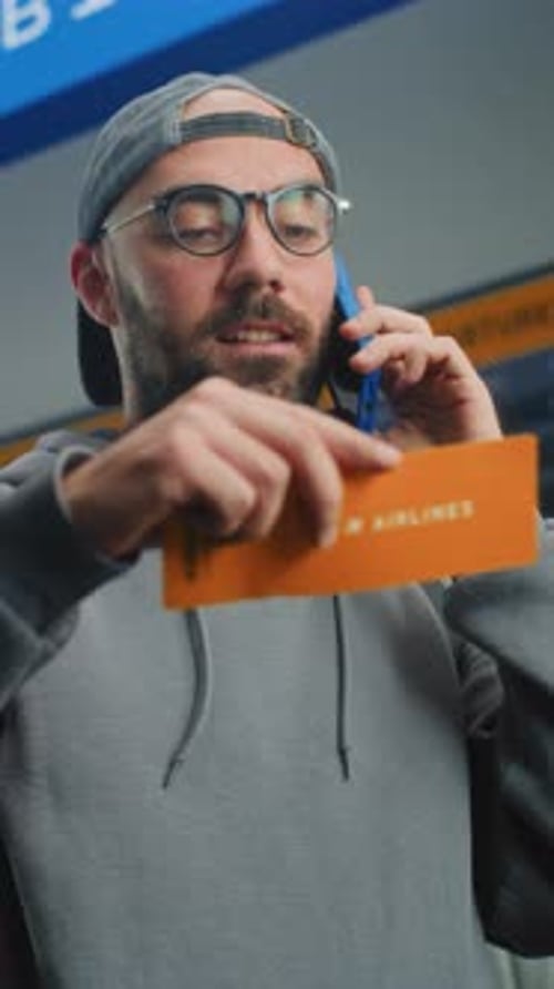 Airport Terminal Man Holding Plane Ticket Talking By Phone to Check Information