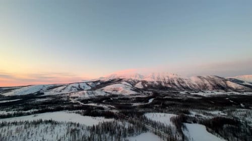 Breathtaking aerial views of snow-covered mountains at sunset in a serene winter wonderland