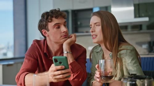 Young Couple Conversing While Man Uses Cell Phone