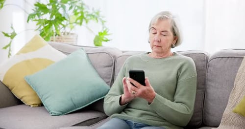 Senior Woman Using Smartphone on Couch Indoors