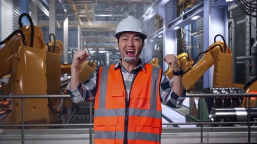 Un ingénieur asiatique crie un objectif célébrant son travail avec des bras robotiques