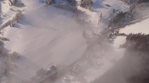 Aerial Scenic Winter Landscape Road Winding Through a Misty Valley Between Snowy Hills