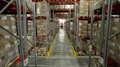 Un chariot élévateur traverse un entrepôt d'usine de carton avec des boîtes