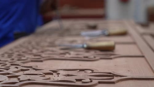 Woodworker Carefully Carving Wood Design in his Workshop