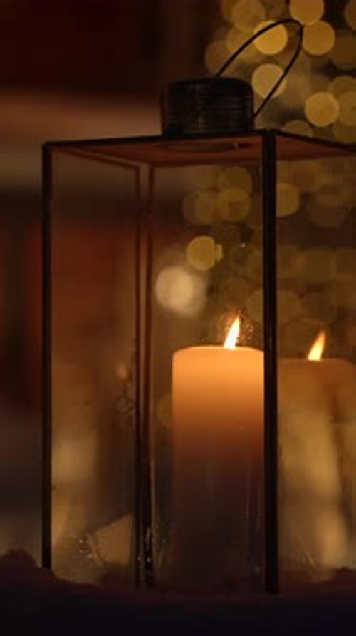 Glowing Candle in Lantern on Snowy Winter Night