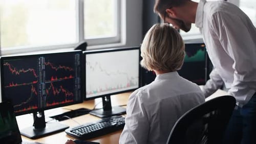 Man with documents sits and showing data. Male and female stockbrokers in formal clothes works