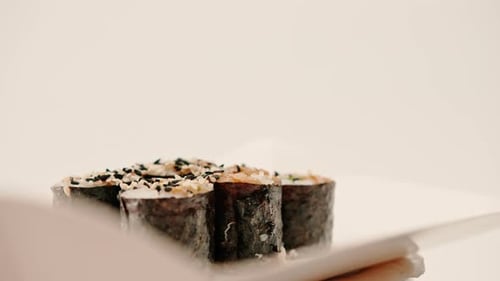 Close-up of maki roll with avocado with soy sauce in sushi delivery box on white background