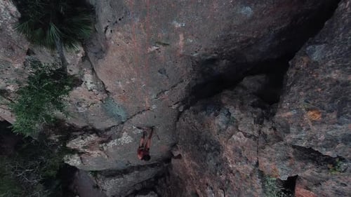 Climbing sportswoman rappelling down the mountain. Drone aerial view of climber woman. Mountain clim