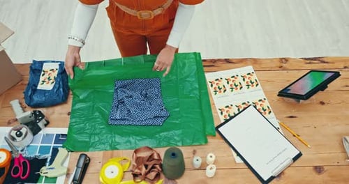 Hands, ecommerce and fashion designer person wrapping a product in office for courier shipping