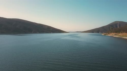 Aerial drone flying over a lake, water dam, with mountains at sunrise. Beautifull dreamy landscape v