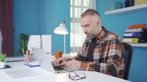 Bearded Man Working on Laptop in Bright Home Office