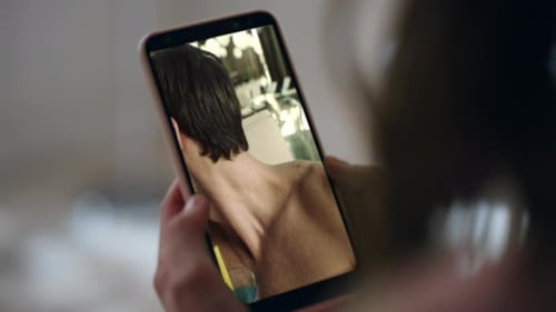 Person holds phone showing man at poolside drinking
