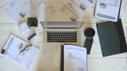 Top View Arms of Young Businessman Looking at Diagrams with Statistics on Papers and Typing Text on