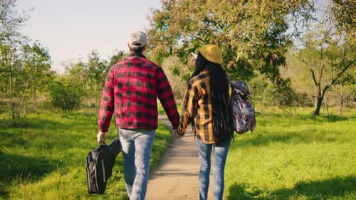 A Couple Walks Hand in Hand Through a Beautifully Lush Green Park on a Sunny Day Fully Cherishing