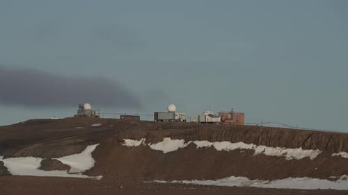 Remote Polar Research Station with Radar Domes Antennas and Buildings Atop a Barren Ridge Bordered