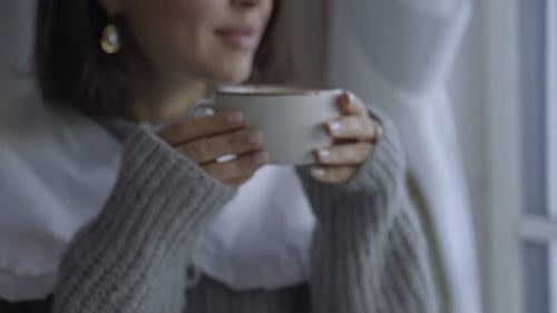 Woman Drinking Coffee and Looking out Window