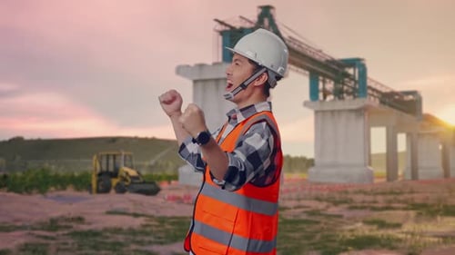 Side View Of Asian Male Engineer Screaming Goal Celebrating Working at Construction Site