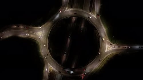 Aerial View of Flowing Nighttime Traffic Circling a Busy Highway Roundabout