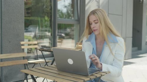 Stylish Freelancer Working On Laptop At Contemporary Street Cafe