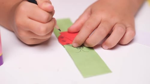 Primer plano: una niña pinta su artesanía de papel con un lápiz