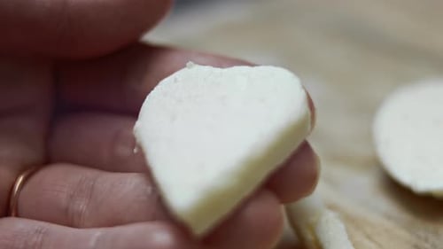 Hand Holding Heart-Shaped Food Item Close-Up