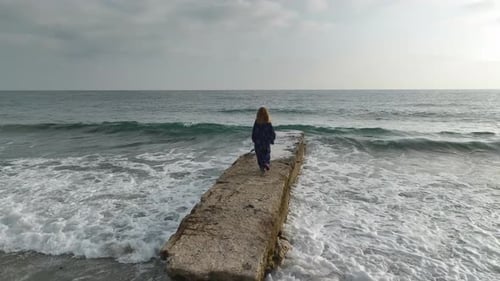 Pier Stroll Aerial of Young Woman Walking on Mediterranean Coast
