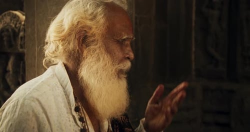 Close-Up of Old Indian Monk Chanting in an Ancient Temple. The Senior Guru Sings Reli