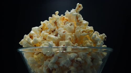 Le pop-corn Air dans un seau à rayures rouges et blanches tourne sur fond noir