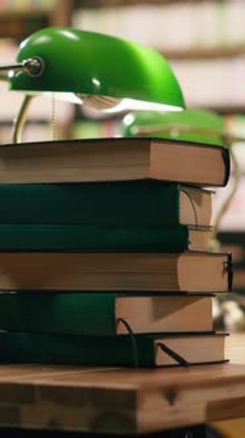 Vertical Video Pile of Hardcover Books on Wooden Desk in Empty College Library