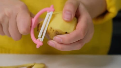 Woman Peeling Potato with Peeler in Bright Light