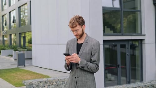 Homme souriant et positif dans une tenue élégante utilisant son smartphone moderne