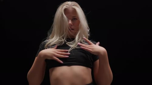 Alluring Young Woman Dancing in Studio Against Black Background