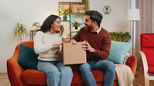 Couple Excitedly Opening Package Together on Couch