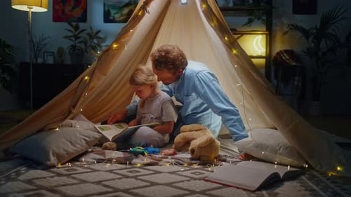Father and Daughter Reading a Book in Tent