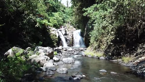 Drone Shot flying towards one of the AlingAling Waterfalls in Bali, Indonesia while tourists can be