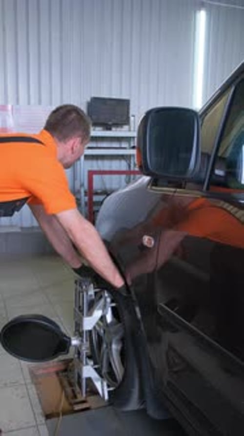 Ein Automechaniker verursacht einen Sturz in einem Auto, Karosseriereparatur, Autoservice, Vertikales Video