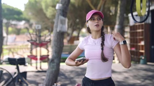 A Fitness Enthusiast is Checking Their Phone While at an Outdoor Gym for Workout Sessions