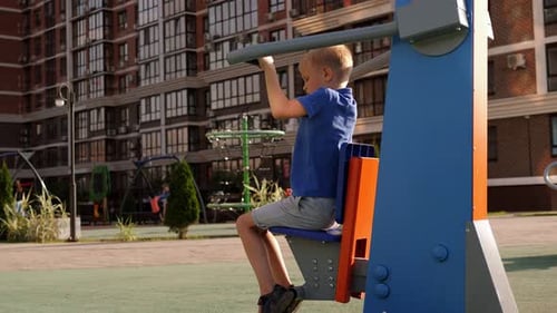 A Small Boy Trains on a Modern Simulator on a Sports Field in the Courtyard