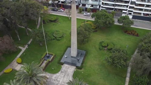 Vidéo d'un Drone 4K montrant un obélisque dans un parc, entouré d'arbres, d'herbe verte et d'un mât de drapeau. Apartme