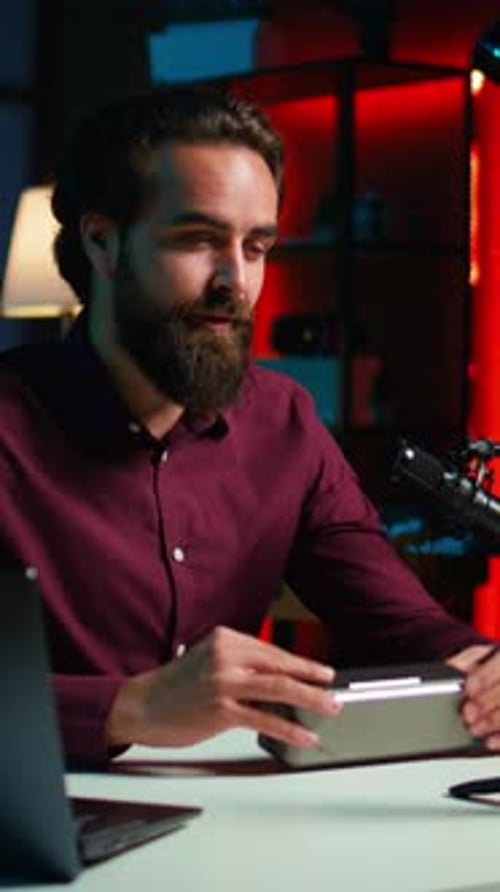 Young Man Inspects Gaming System at Desk