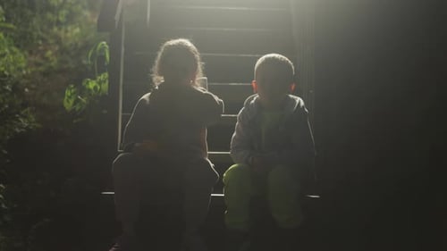 Children Sitting on Wooden Steps in Sunny Forest