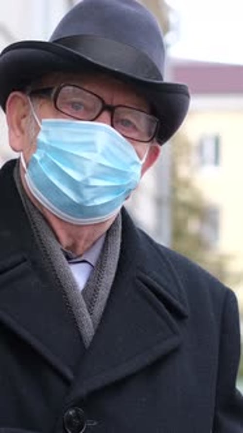 Senior Adult Adjusting Face Mask Outdoors