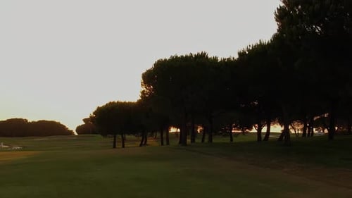 Golf course at sunset with a sunny sunset sky. Air travelling at low altitude over the golf course.