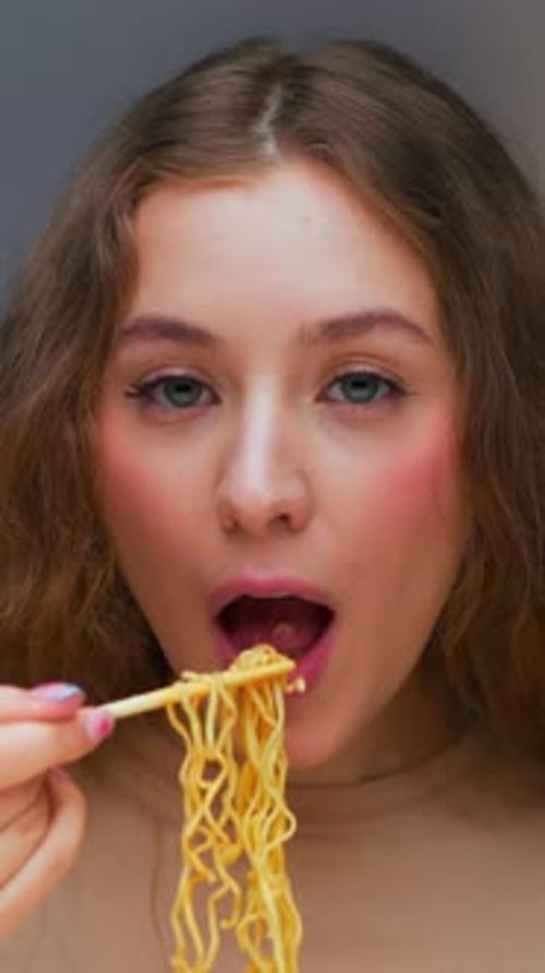 Girl Eating Noodles with Chopsticks in Close Up