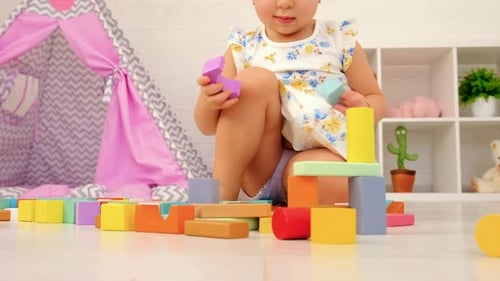 Little Girl Playing with Colorful Wooden Blocks at Home