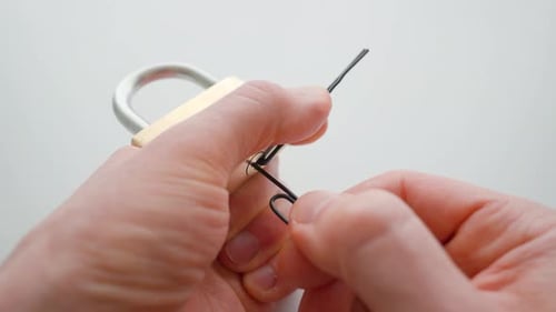 Man picking a lock with paper clips. Lock picking demonstration. Close up