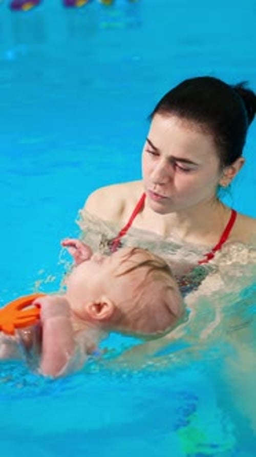 Sweet Caucasian infant baby lies on the water in the swimming pool.
