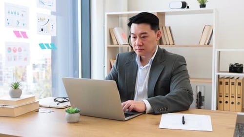 Professional Asian Businessman Using Headset During Video Call in Office