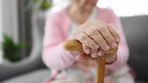 Senior Woman Hands Resting on Wooden Cane
